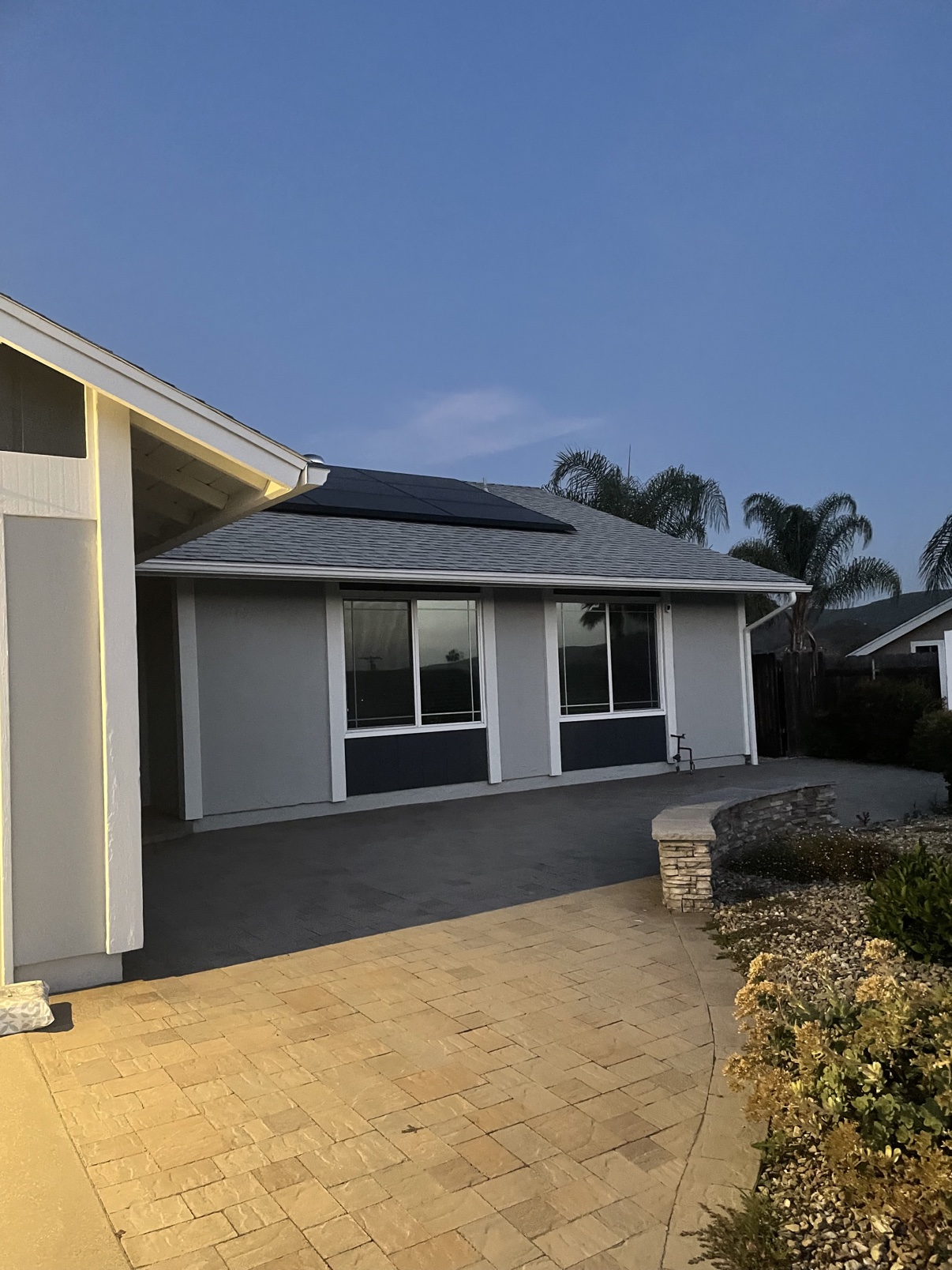 Home exterior with fresh siding, dark trim, and paved patio