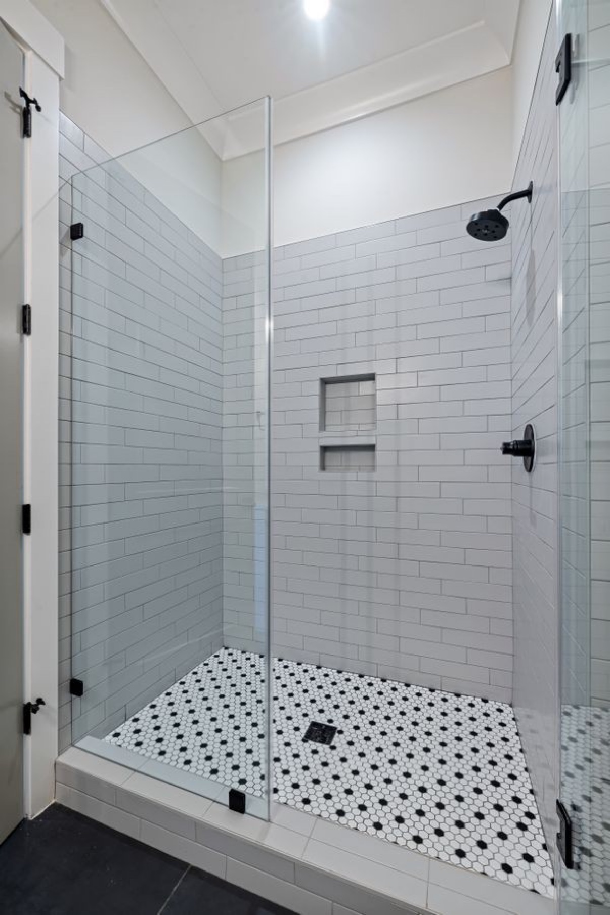 Walk-in shower with gray wall tile, pebble floor, and glass enclosure