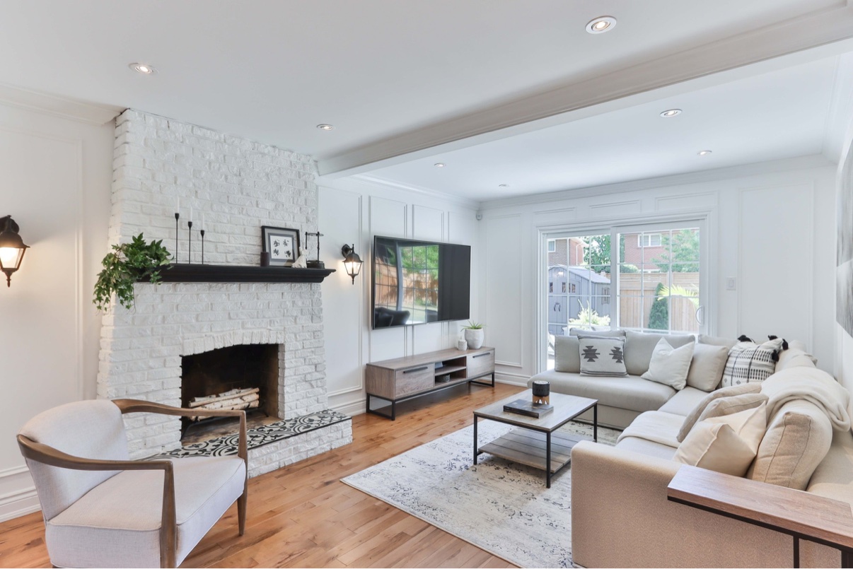 Bright open-plan living room with fireplace, seating, and large windows